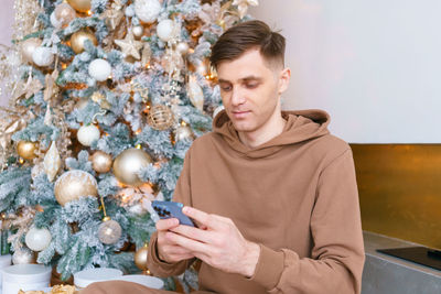 Successful man using smartphone against an christmas tree. social media public
