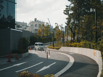 Road by buildings against sky in city