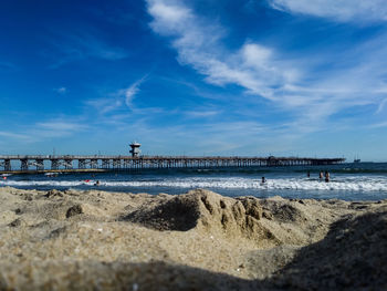 Pier on beach against blue sky