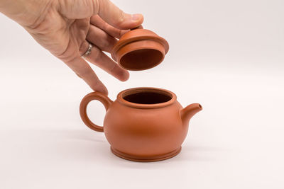 Close-up of hand holding coffee cup against white background