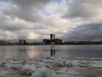 Scenic view of frozen sea by buildings against sky