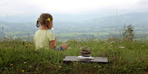 Cute girl relaxes in the mountains. stack of zen stones and digital gadget, laptop and mobile phones