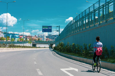 Rear view of woman riding bicycle on road in city