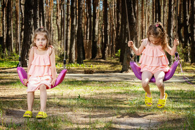 Sisters swinging against trees