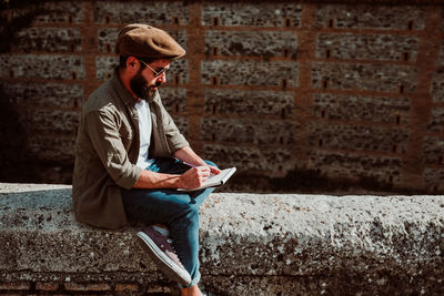 Man writing in book while sitting outdoors