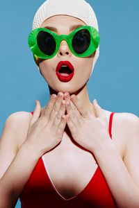 Close-up of woman wearing sunglasses against blue background