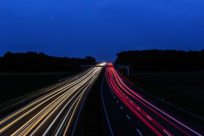 Light trails on highway against sky at night