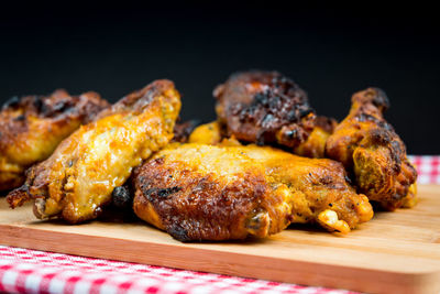 Close-up of fried chicken wings on cutting board against black background