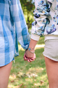 Midsection of friends holding hands at park