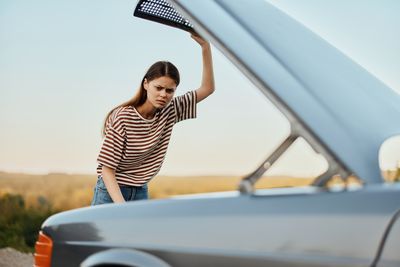 Portrait of young woman sitting on car