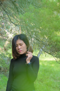 Young woman looking away while standing on field