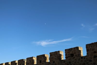 Low angle view of fortified wall against blue sky