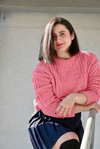 Portrait of beautiful woman standing against pink wall