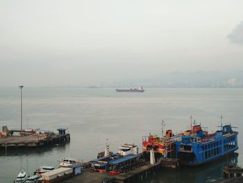 Boats moored at harbor against sky