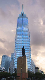 Low angle view of skyscrapers against cloudy sky