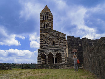 Woman standing at historic building against sky