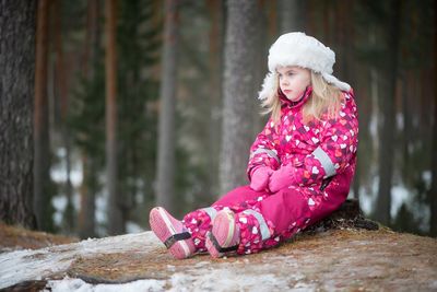Girl sitting on tree stump in forest