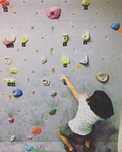 Rear view of girl climbing on wall