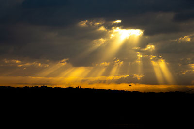Silhouette landscape against dramatic sky during sunset