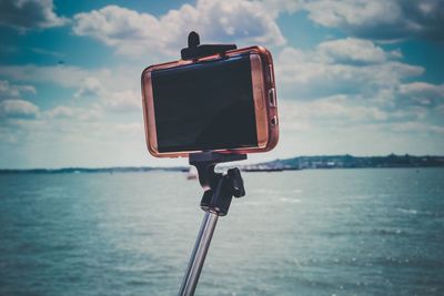 Close-up of smart phone against sky