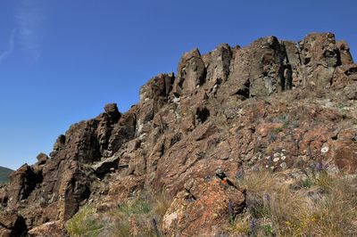 Low angle view of rocky mountains against clear blue sky