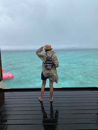 Rear view of man looking at sea against sky