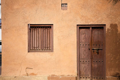 A weathered exterior house wall, with a closed window and door