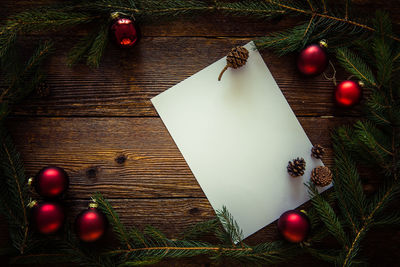High angle view of christmas decorations with blank paper on wooden table