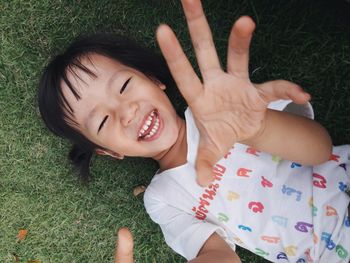 Directly above portrait of happy girl lying on grassy field