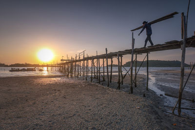 Man standing on beach against sky during sunset