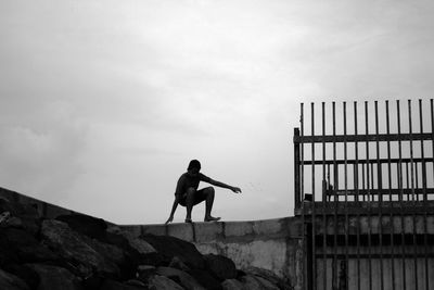 Silhouette man standing on rock against sky