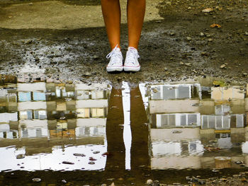 Low section of woman standing by puddle