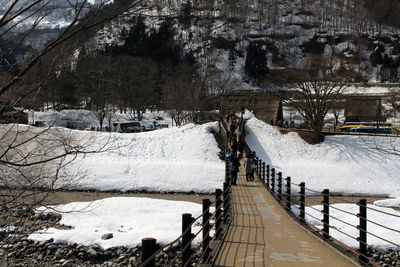 Snow covered footpath by railing during winter