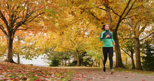 Full length of young woman jogging in park during autumn