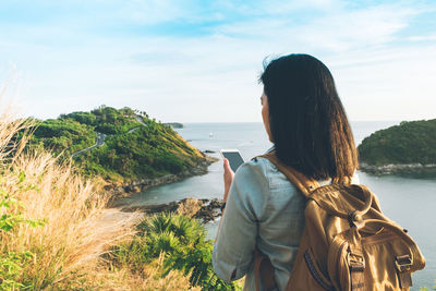 Rear view of woman standing on beach against sky