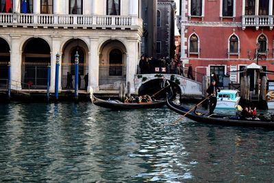 People on boats in canal along buildings