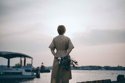 Rear view of man looking at sea against sky