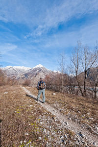 Rear view of man walking on mountain against sky