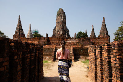 Rear view of woman standing outside temple against building