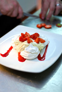 Chef preparing pavlova with fresh strawberries and cream