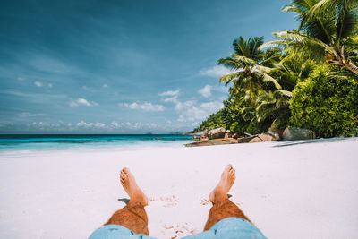 Low section of person on beach against sky