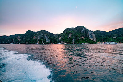 Scenic view of sea and mountains against sky at sunset