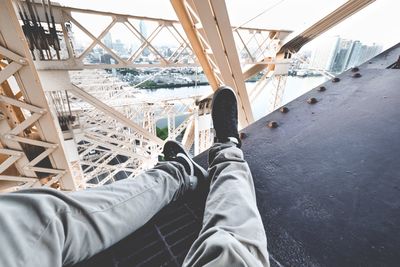 Low section of man sitting on bridge