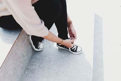 Low section of woman tying shoelace while sitting on steps