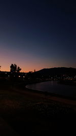 View of illuminated city against clear sky at sunset