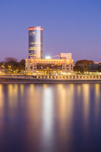 Reflection of illuminated buildings in city at waterfront