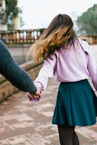 Cropped image of man holding hands of woman while walking on street