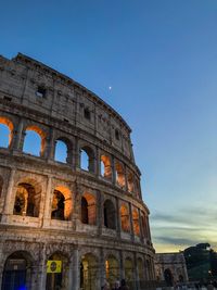 Low angle view of coliseum against blue sky