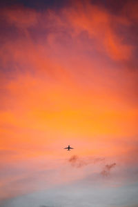 Low angle view of airplane flying against sky during sunset
