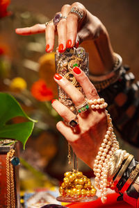 Cropped hands of woman holding champagne flute with jewelry